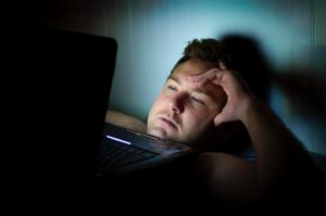 Man with insomnia looking at laptop screen in the dark